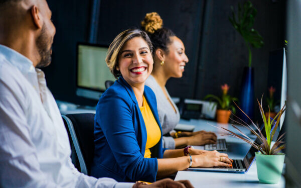 Woman smiling at camera while at computer desk working her recruiting jobs