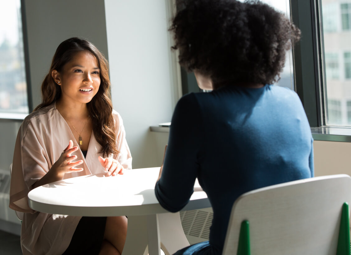 Two women staffing consultants sitting across the table from one another having a meeting